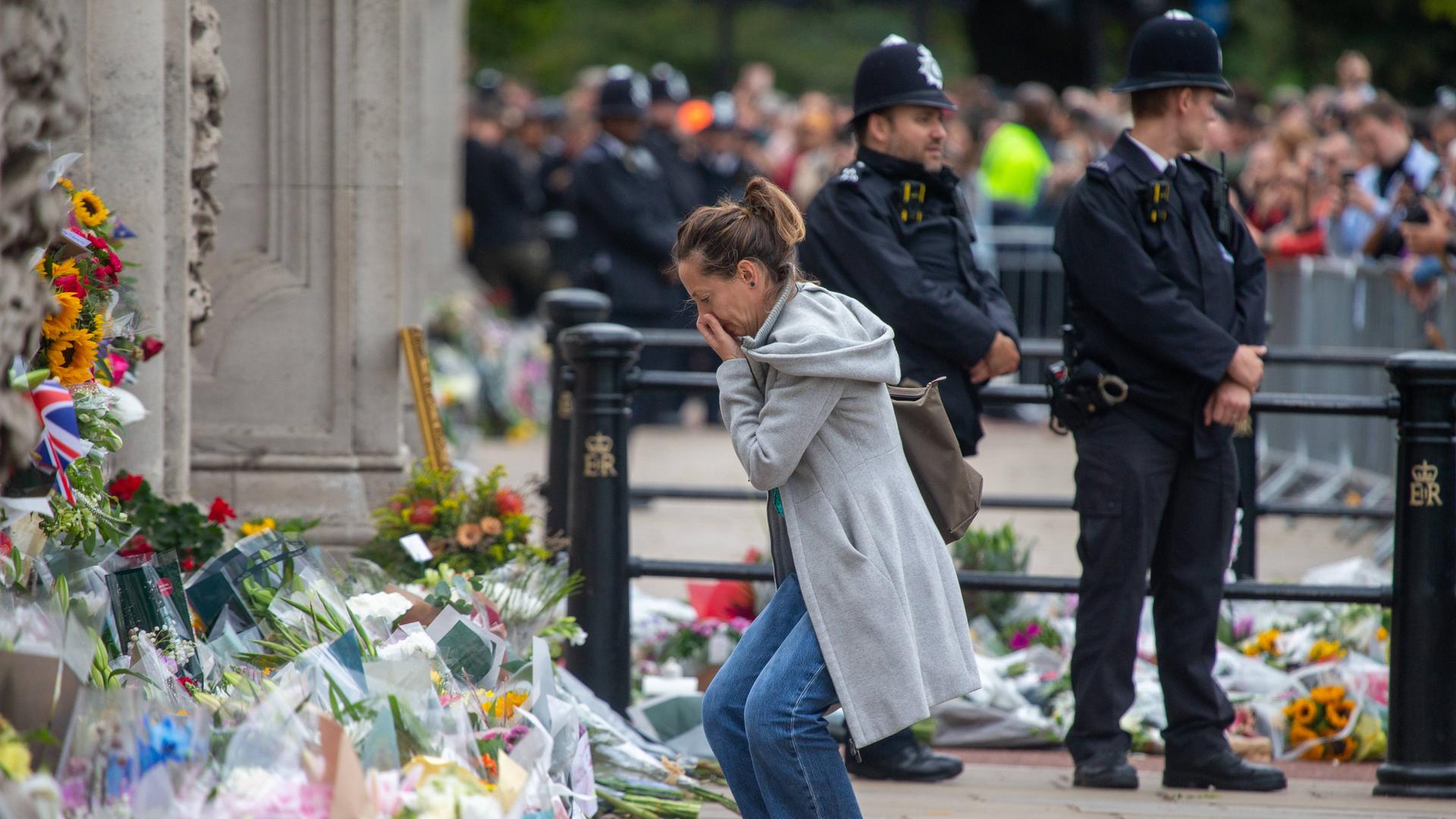 Menschen legen zum Gedenken an die verstorbene Königin Elizabeth II. Blumen am Buckingham Palast in London ab