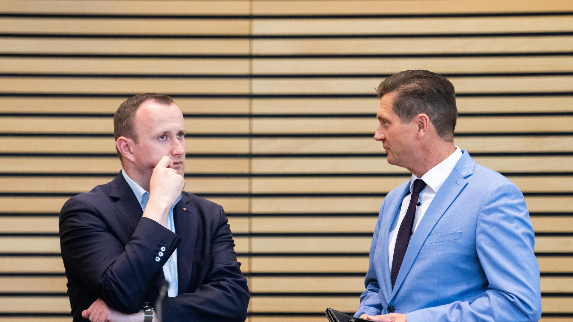 Im Gespräch: Christian Herrgott (CDU, links) mit AfD-Herausforderer Uwe Thrum (AfD) im Thüringer Landtag. Herrgott trägt einen dunklen Anzug, er schaut nachdenklich. Thrum hält eine Brieftasche in der Hand, er trägt ein hellblaues Sakko. 