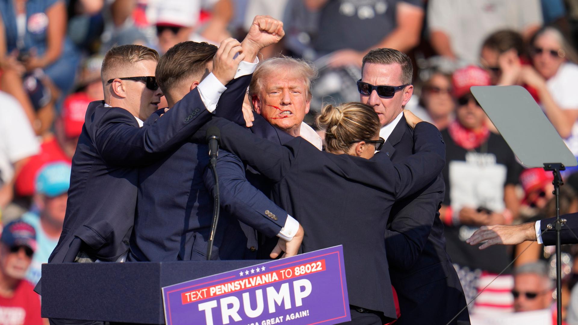 Der republikanische Präsidentschaftskandidat und ehemalige Präsident Donald Trump wird am Samstag, den 13. Juli 2024, bei einer Wahlkampfveranstaltung in Butler, Pennsylvania, von der Bühne geholfen.