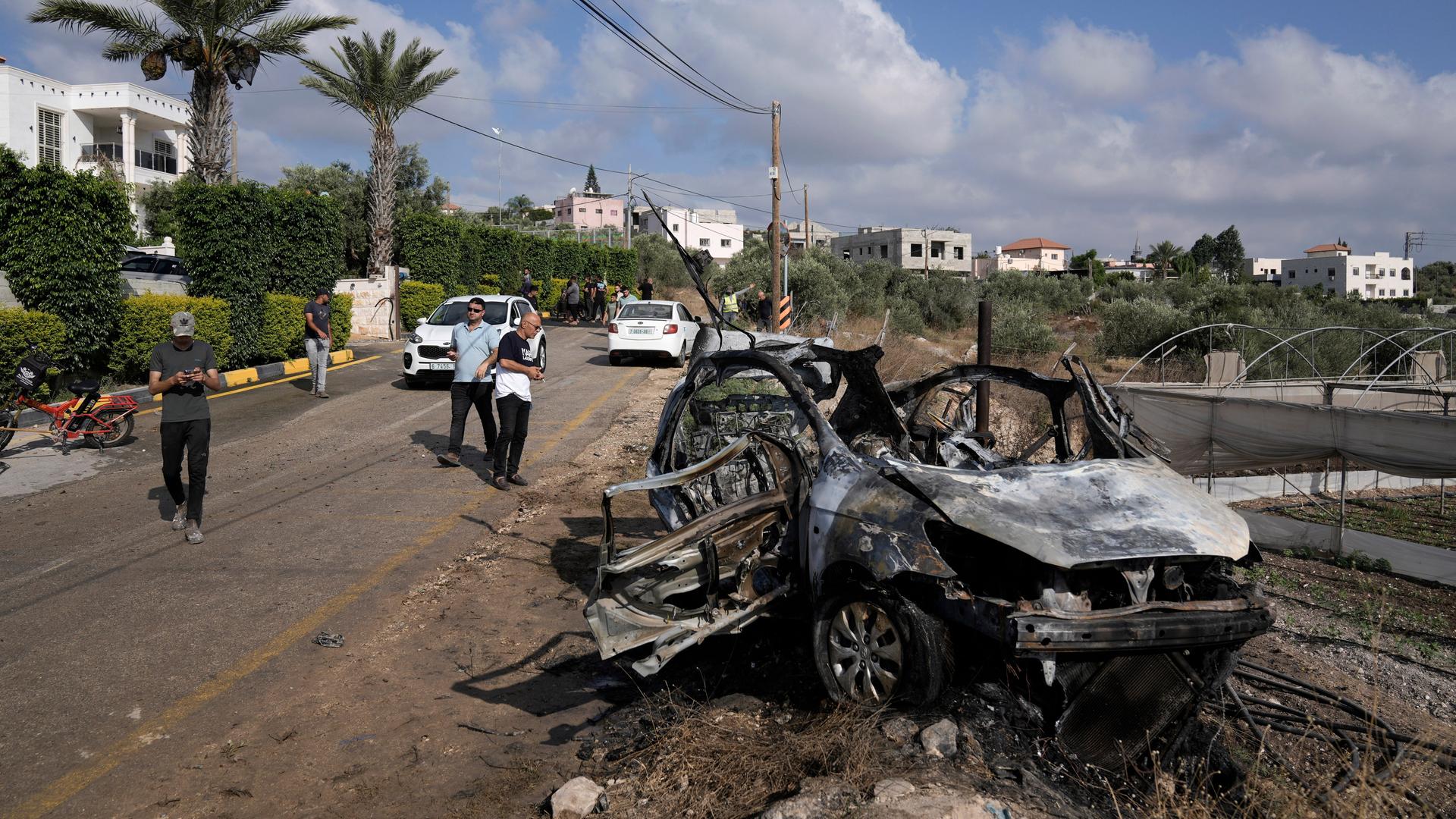 Palästinenser versammeln sich um ein Auto, das bei einem Drohnenangriff zerstört wurde. 