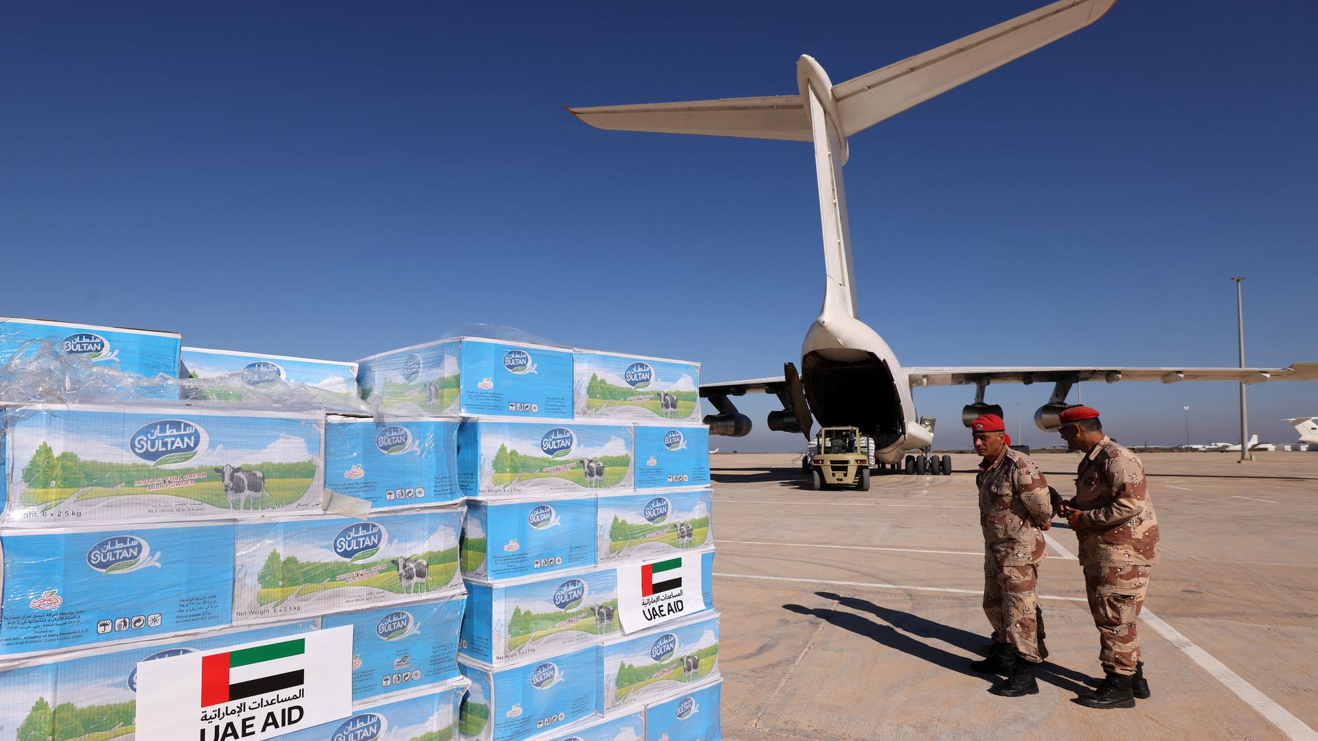 Militärangehörige überwachen auf dem Flughafen von Bengasi die Ankunft von Hilfsgütern. Im Vordergrund stehen Paletten mit Kartons, im Hintergrund ist eine Frachtmaschine.