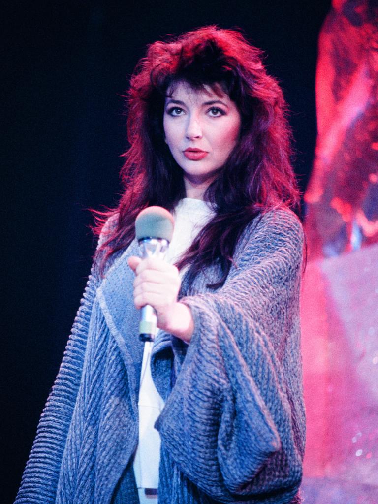 Eine Frau mit dunklen, langen Haaren hält ein Mikrofon. Durch die Beleuchtung hintrelässt ihr Haar an den Konturen einen rötlichen Eindruck.