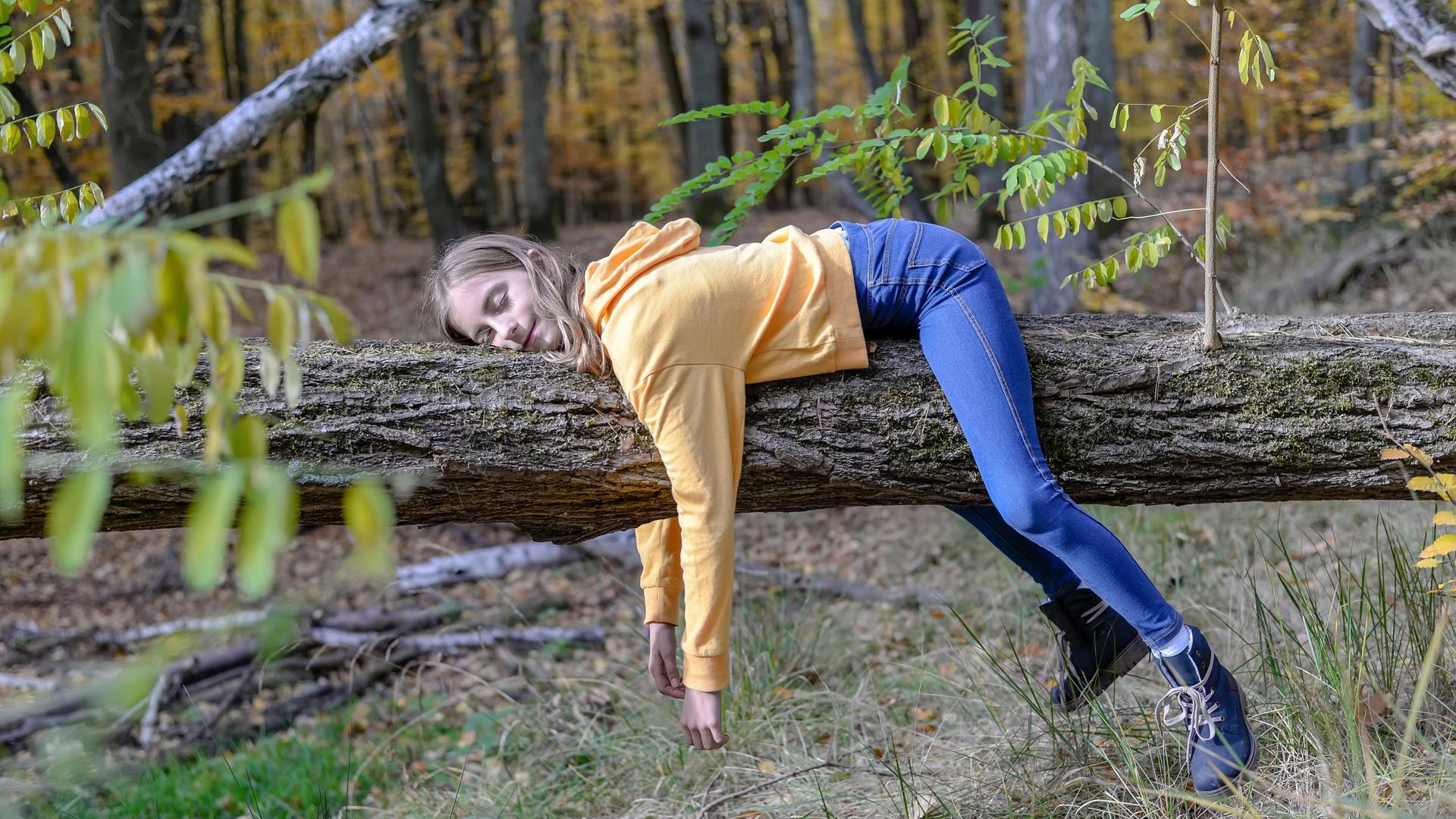 ein Mädchen hängt in Faultierpose über einem Ast ein Mädchen hängt in Faultierpose über einem Ast