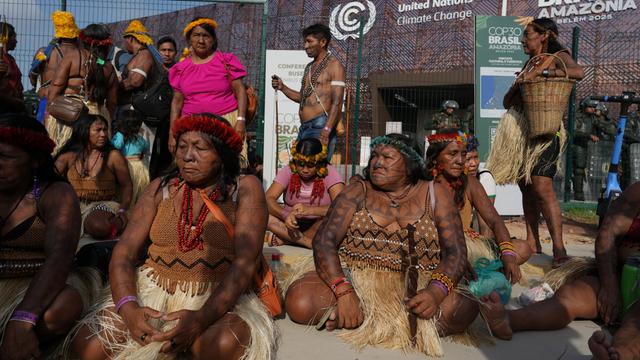 Indigene Menschen sitzen und stehen vor dem Eingang von der Welt-Klima-Konferenz. 