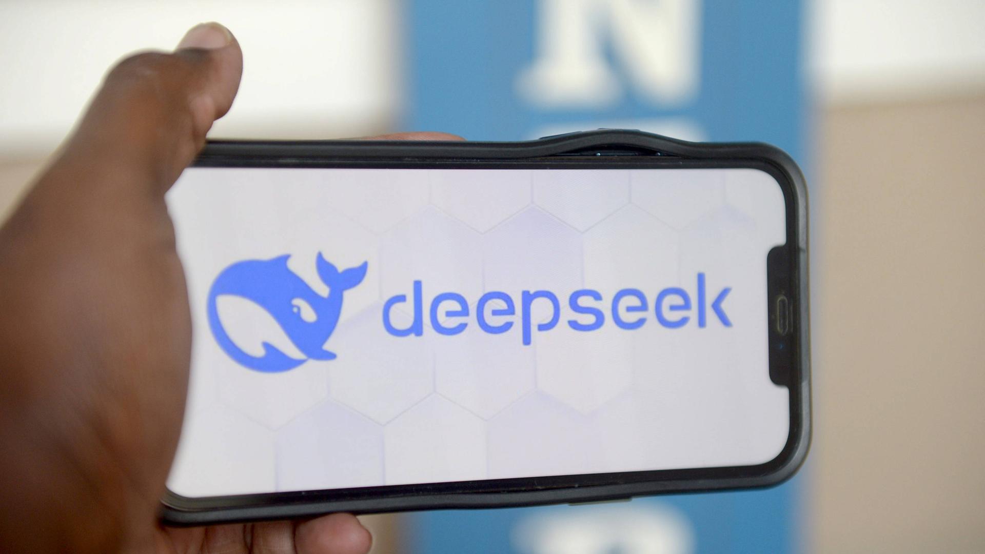 Eine Hand hält ein Smartphone auf dem das Logo der chinesischen KI Deepseek zu sehen ist.