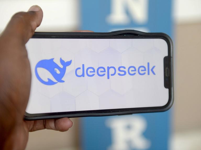 Eine Hand hält ein Smartphone auf dem das Logo der chinesischen KI Deepseek zu sehen ist.