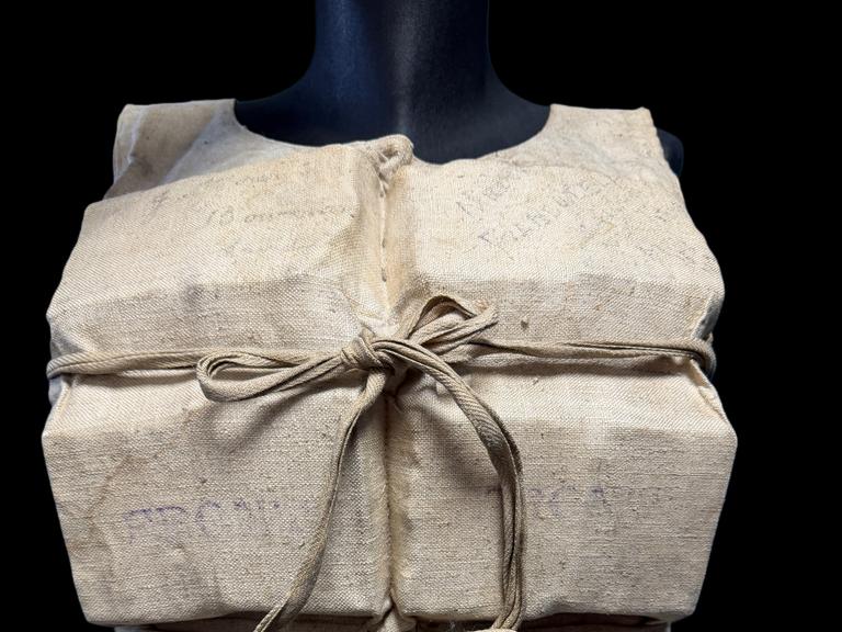 Eine alte Rettungsweste der Titanic. Der Bezug ist beige und die Weste ist vorne geschnürt.