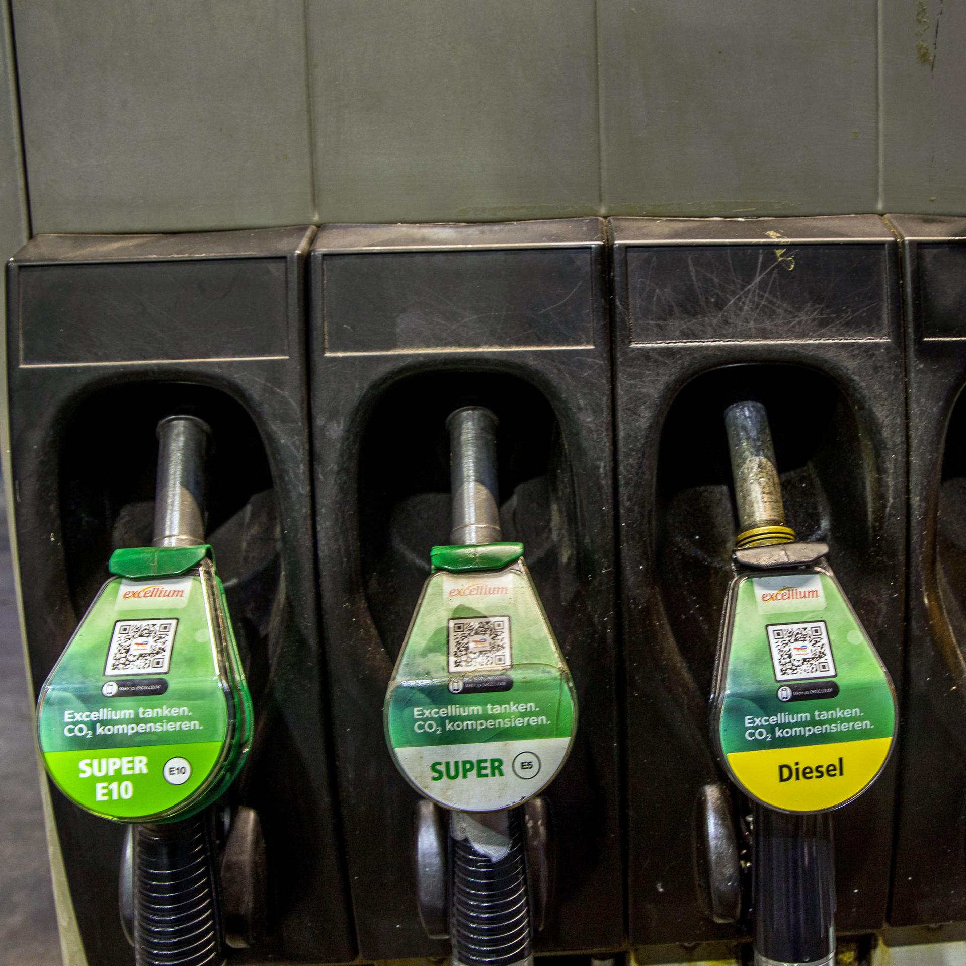 Zapfpistolen für die Kraftstoffe Benzin Super E10, Benzin Super E5, Diesel und excellium Diesel hängen an einer Zapfsäule 