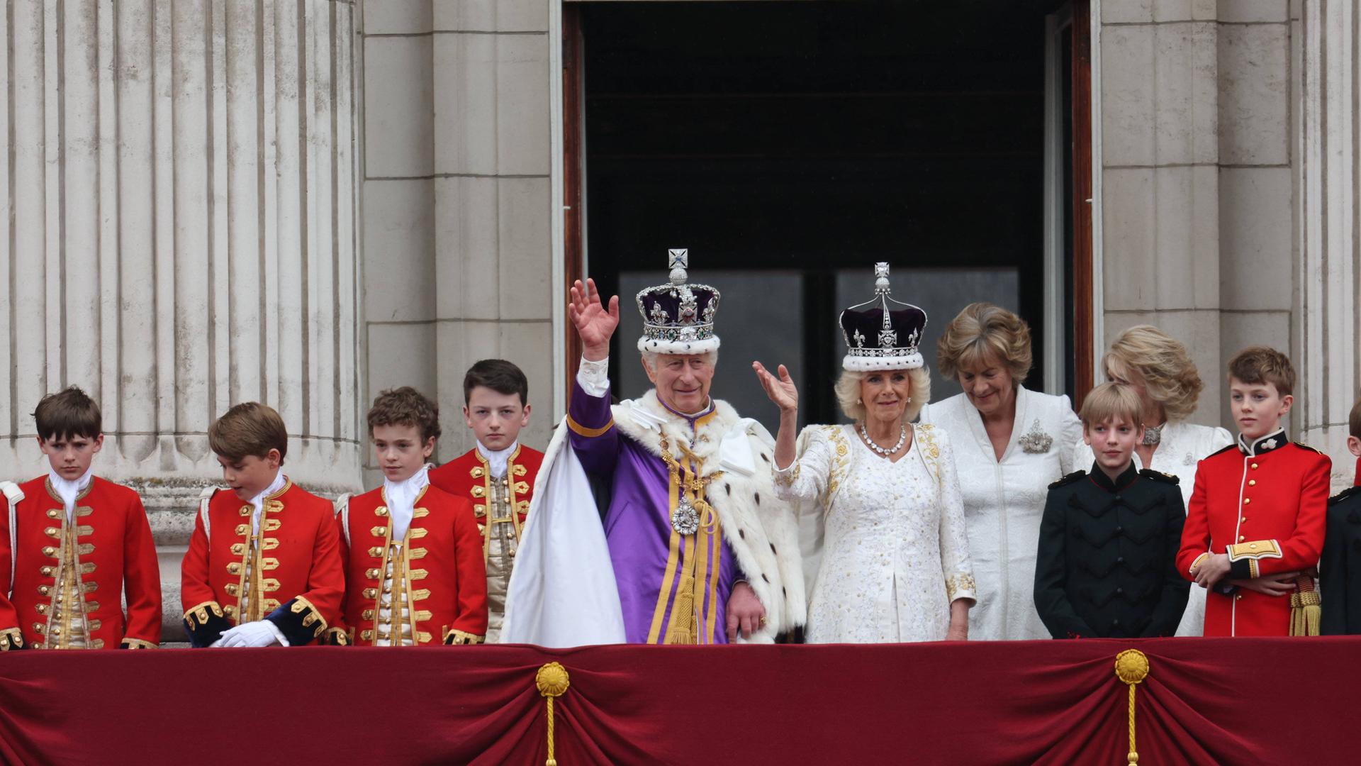 Charles und Kamilla stehen auf dem Balkon des Buckingham Palace und winken. Charles und Kamilla stehen auf dem Balkon des Buckingham Palace und winken.