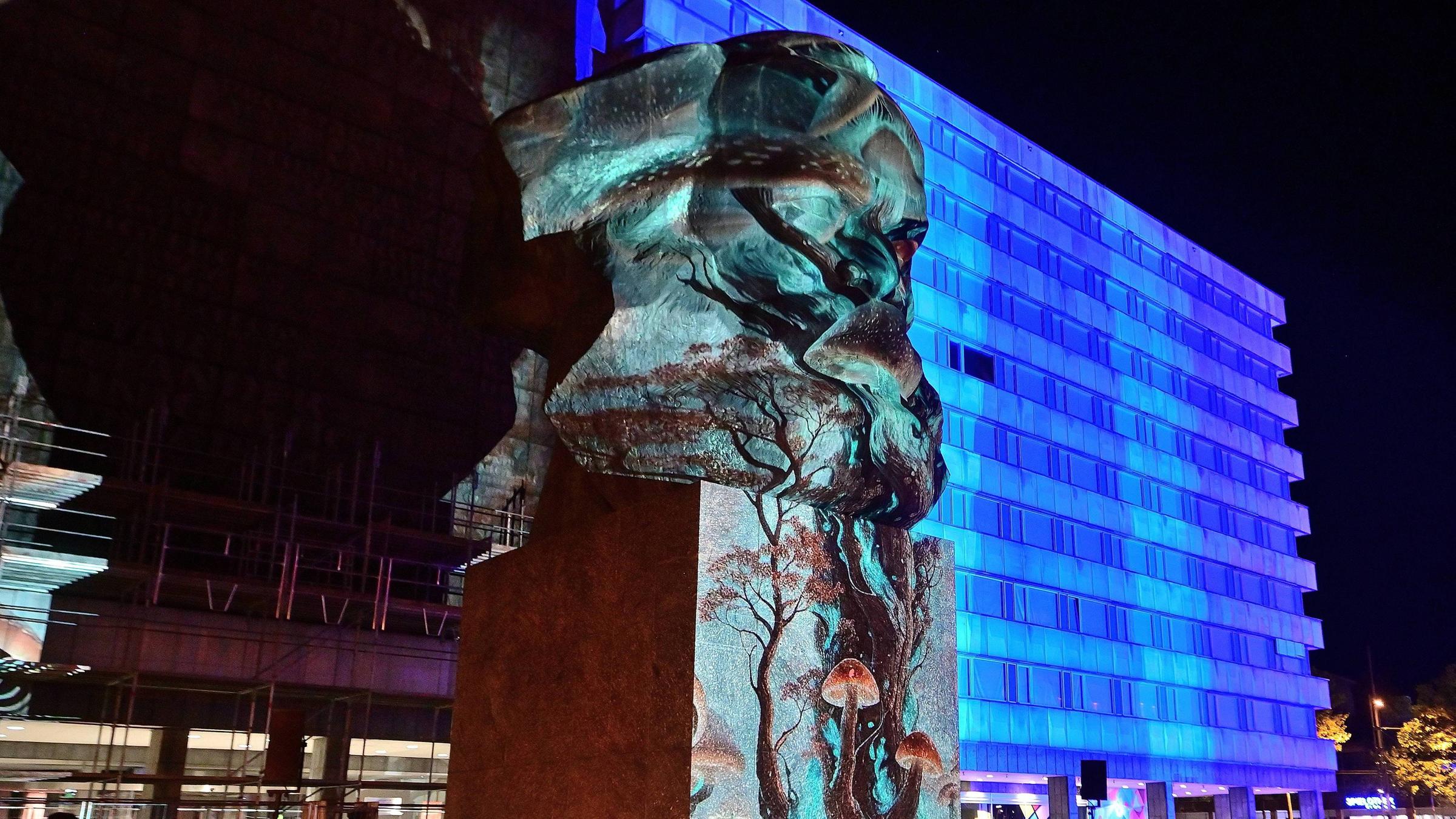 In Chemnitz werden die Büste von Karl Marx und Gebäude mit blauem Licht und Mustern angestrahlt.