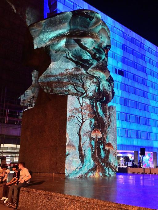 In Chemnitz werden die Büste von Karl Marx und Gebäude mit blauem Licht und Mustern angestrahlt.