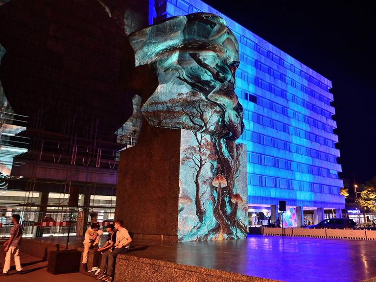 In Chemnitz werden die Büste von Karl Marx und Gebäude mit blauem Licht und Mustern angestrahlt.