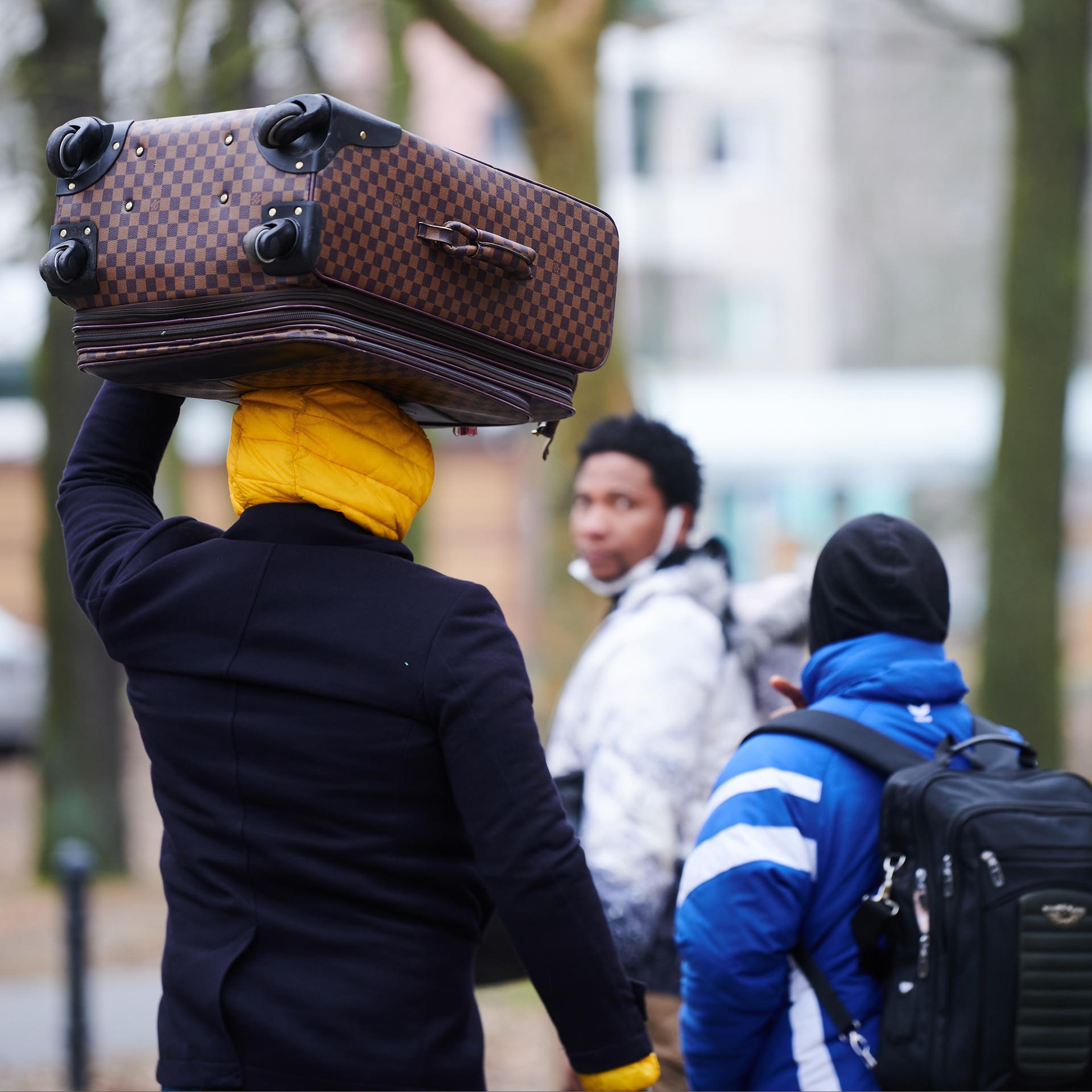Flüchtlinge tragen ihre Koffer auf dem Kopf, während sie ins Ankunftszentrum Reinickendorf gehen. 