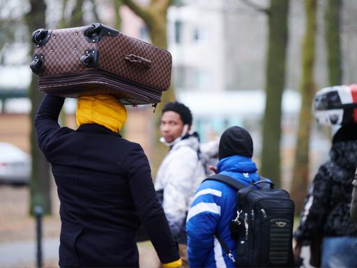 Flüchtlinge tragen ihre Koffer auf dem Kopf, während sie ins Ankunftszentrum Reinickendorf gehen. 