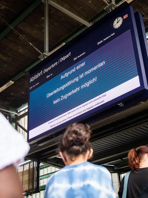 Während Fahrgäste in der Schlange zum DB Infoschalter anstehen, informiert eine Anzeigetafel im Stuttgarter Hauptbahnhof die Fahrgäste darüber, dass der Zugverkehr wegen eines Oberleitungsschadens aktuell nicht möglich ist.