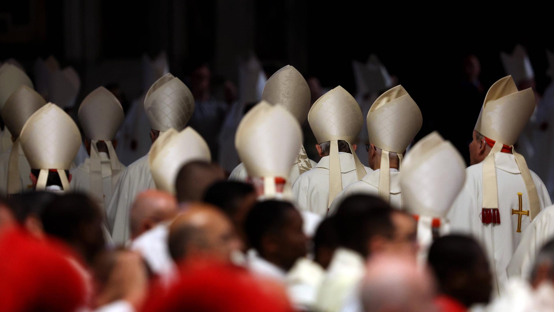 Kardinäle verlassen die Basilica nach einer Messe. Die Kardinälshüte sind von hinten zu sehen.