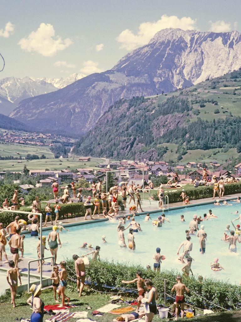 Gut gefülltes Schwimmbad vor der Kulisse der Alpen an einem sonnigen Sommertag Ötz in Österreich. Historische, kolorierte Postkarte.