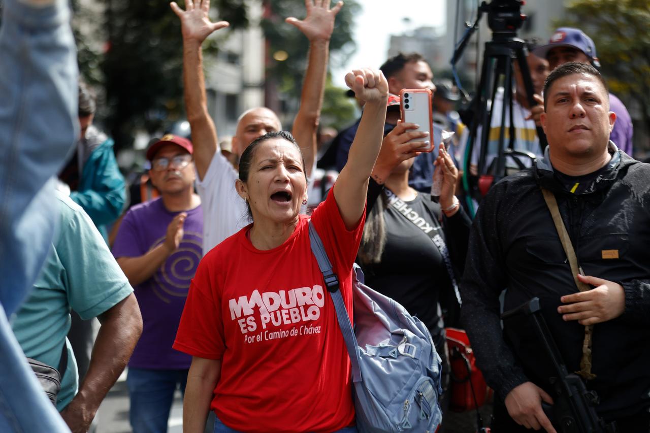 Mehrere Menschen schreien und recken die Arme in die Höhe. Auf dem T-Shirt einer Frau steht: "Maduro ist das Volk". Mehrere Menschen schreien und recken die Arme in die Höhe. Auf dem T-Shirt einer Frau steht: "Maduro ist das Volk".