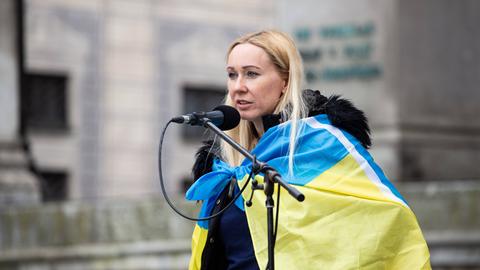 Daria Onyshchenko am Mikrofon mit Ukraine-Flagge um die Schultern.