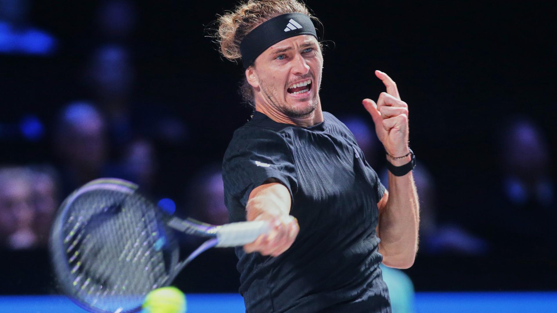 Alexander Zverev trägt ein schwarzes Trikot und ein schwarzes Schweißband um die Stirn. Er holt zum Schlag mit seinem Tennisschläger aus.  Alexander Zverev trägt ein schwarzes Trikot und ein schwarzes Schweißband um die Stirn. Er holt zum Schlag mit seinem Tennisschläger aus.