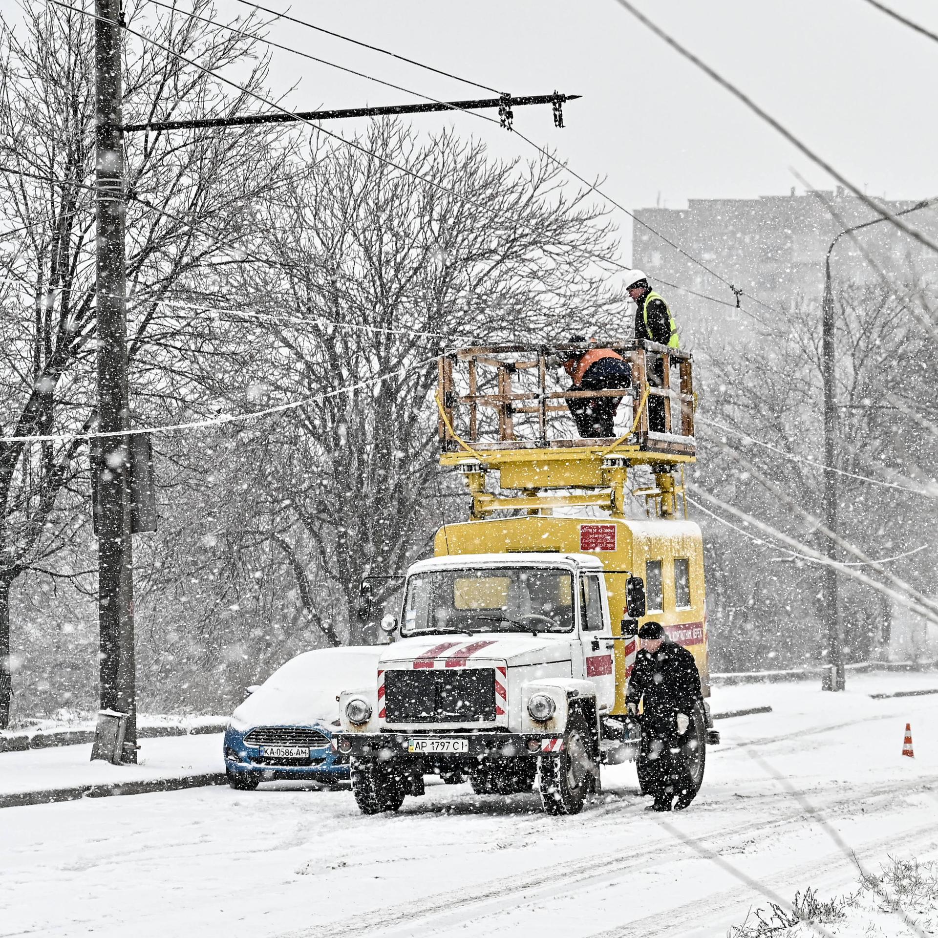 Elektriker reparieren Stromleitungen mitten im Schneefall. 