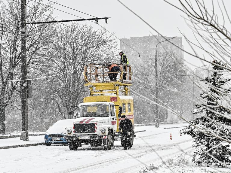 Elektriker reparieren Stromleitungen mitten im Schneefall. 