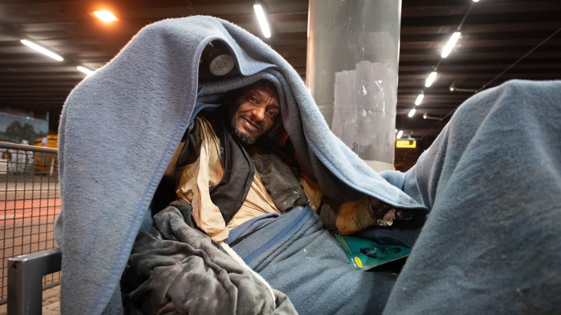 Obdachlose Person  auf einer Bank am U-Bahnhof Galluswarte bedeckt sich mit einer Decke