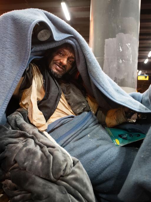 Obdachlose Person  auf einer Bank am U-Bahnhof Galluswarte bedeckt sich mit einer Decke