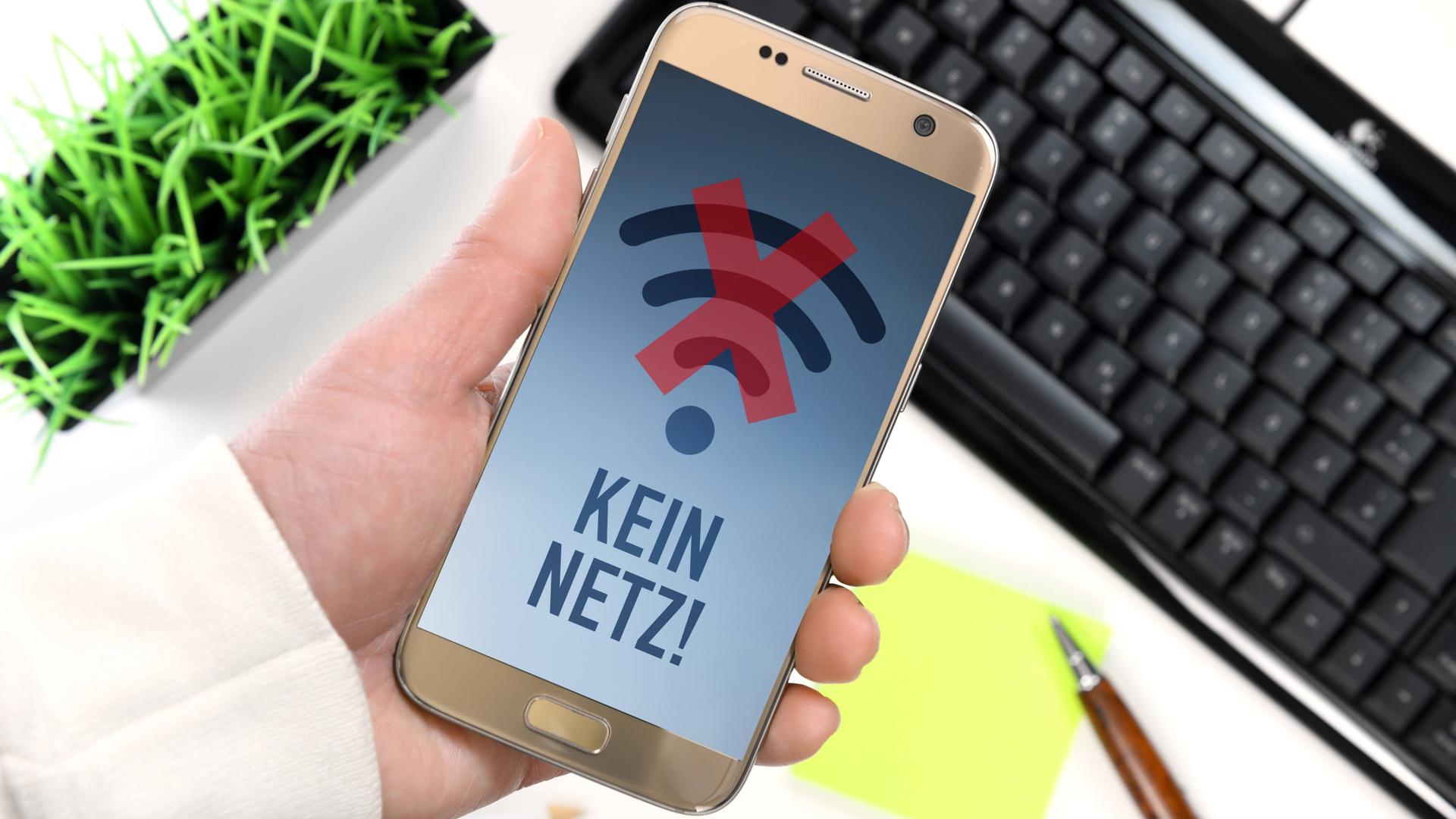 Eine Hand hält ein Smartphone hoch. Das Smartphone hat keinen Empfang. Auf dem Bildschirm steht "Kein Netz". Eine Hand hält ein Smartphone hoch. Das Smartphone hat keinen Empfang. Auf dem Bildschirm steht "Kein Netz".