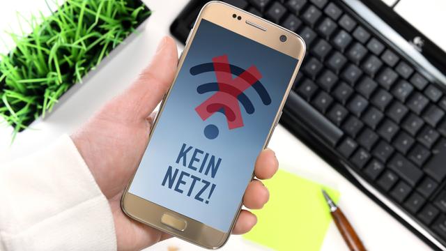 Eine Hand hält ein Smartphone hoch. Das Smartphone hat keinen Empfang. Auf dem Bildschirm steht "Kein Netz".