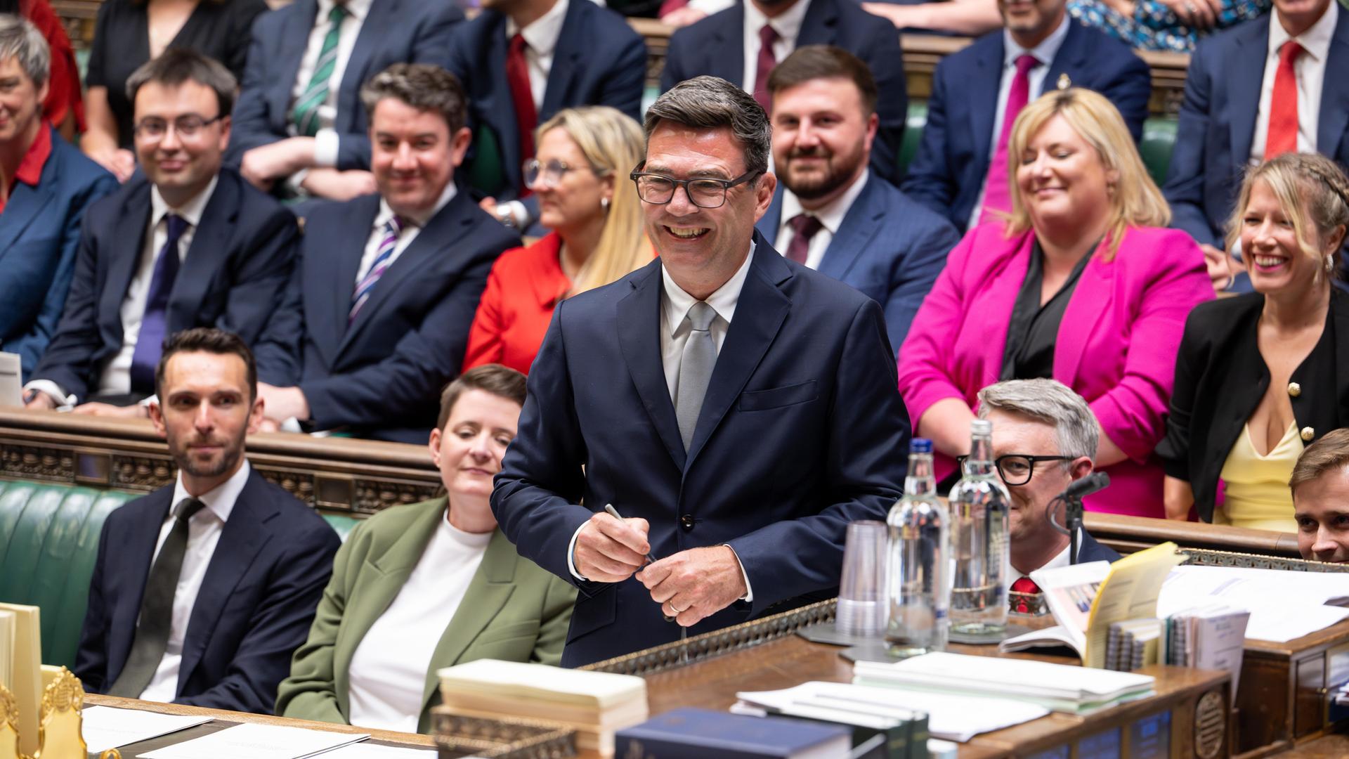 Andy Burnham steht während seiner Vereidigung als Abgeordneter im britischen Unterhaus und lächelt. Andy Burnham steht während seiner Vereidigung als Abgeordneter im britischen Unterhaus und lächelt.