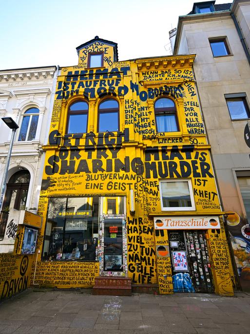 Der Buchladen "Golden Shop" in der Fehrfeld-Straße mit gelber Fassade und Graffitti-Aufschriften