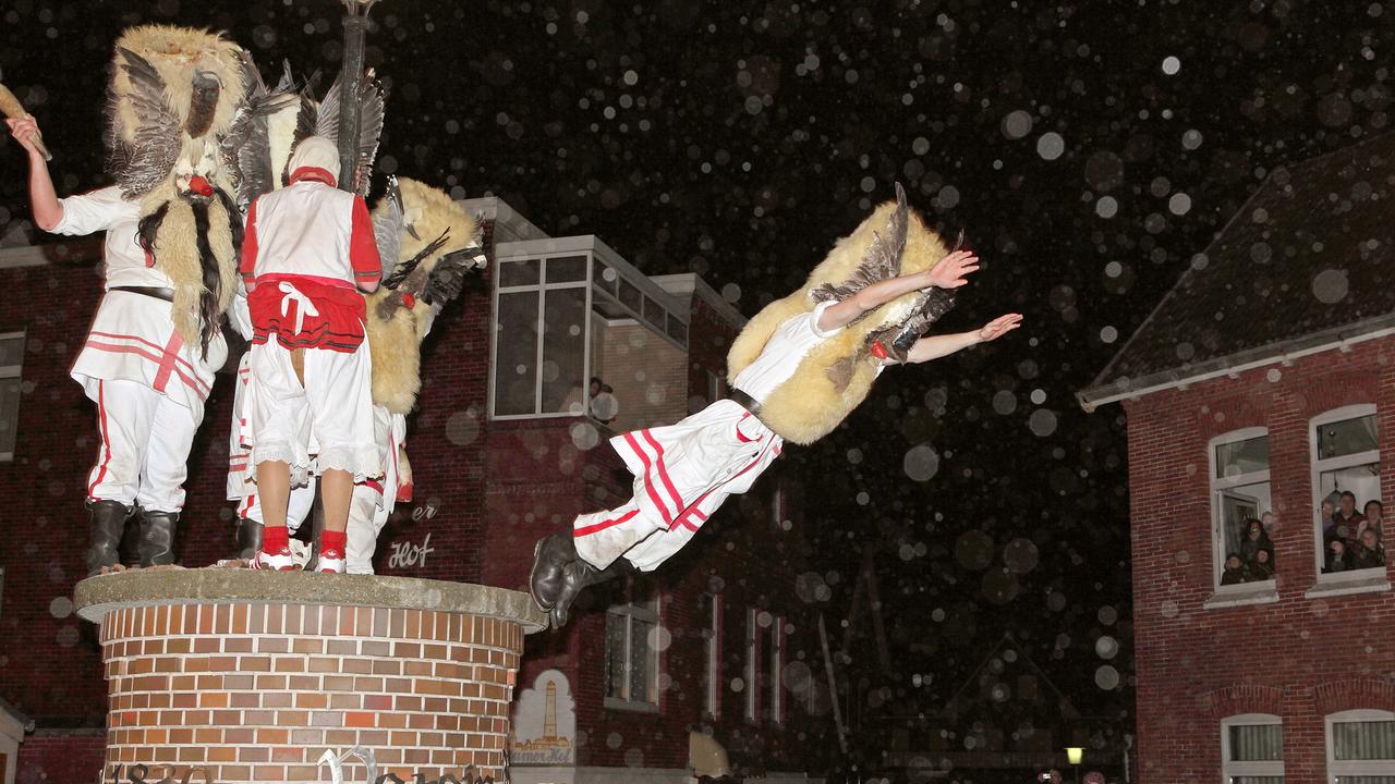 Mit Masken verkleidete Männer des Vereins Borkumer Jungens stürzen sich am Abend (Aufnahme vom 05.12.2011) in der Innenstadt der Nordseeinsel von einer Litfasssäule in die Arme der Schaulustigen.