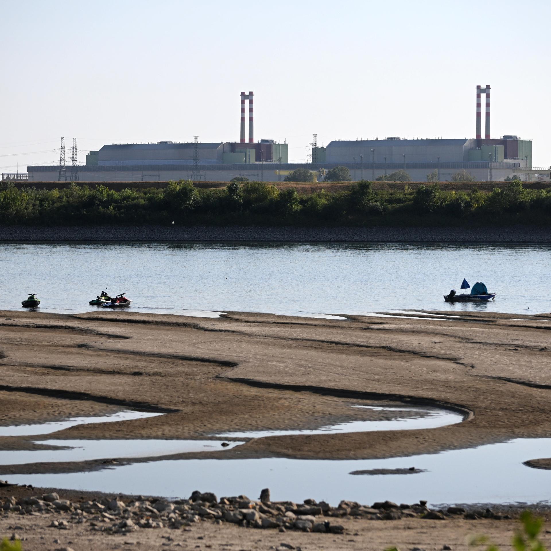 Das ungarische Atomkraftwerk Paks vom Ufer der Donau aus fotografiert. Der Fluss führt wenig Wasser und Sandbänke treten hervor.