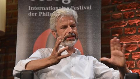 Der Mediziner und Autor Tobias Esch spricht und diskutiert auf der phil.COLOGNE. Er hat die Hände erhoben. 