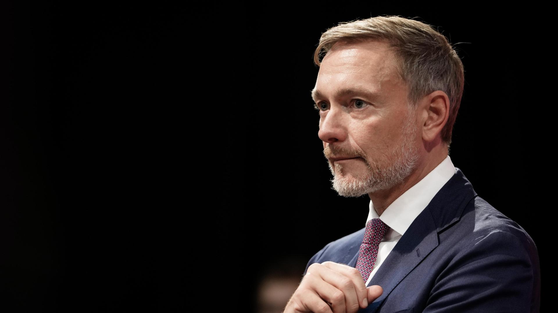 Christian Lindner, Bundesfinanzminister von der FDP, nachdenklich vor dunklem Hintergrund.