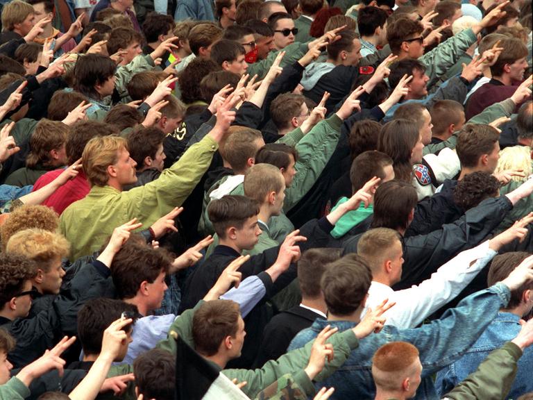 Teilnehmer eines "Trauermarsches" in Dresden für den erschossenen Neonazi Rainer Sonntag. Viele junge Männer bilden einen Pulk und heben ihre Hände zum Hitlergruß, wobei sie Zeige- und Mittelfinger spreizen.