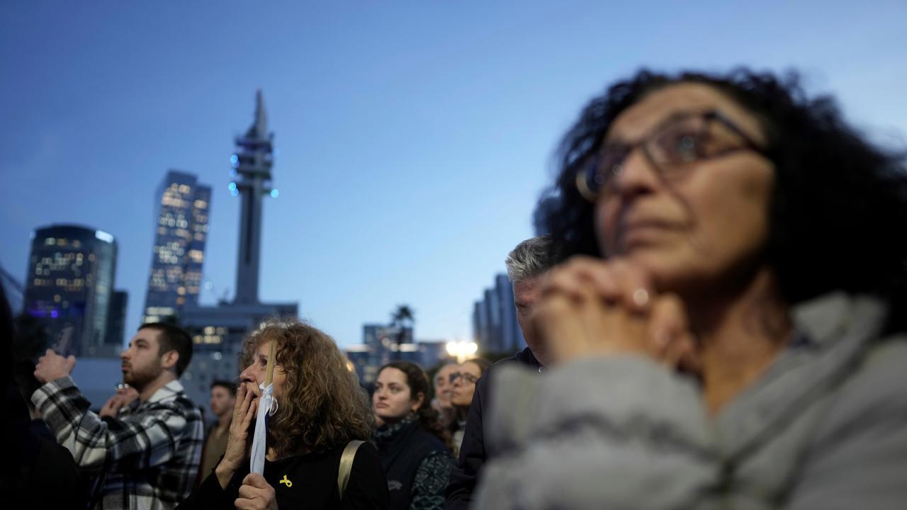 Menschen stehen vor Hochhäusern beieinander. Eine Frau im Vordergrund hat die Hände wie für ein Gebet gefaltet. Es sind Angehörige von Geiseln der Hamas.