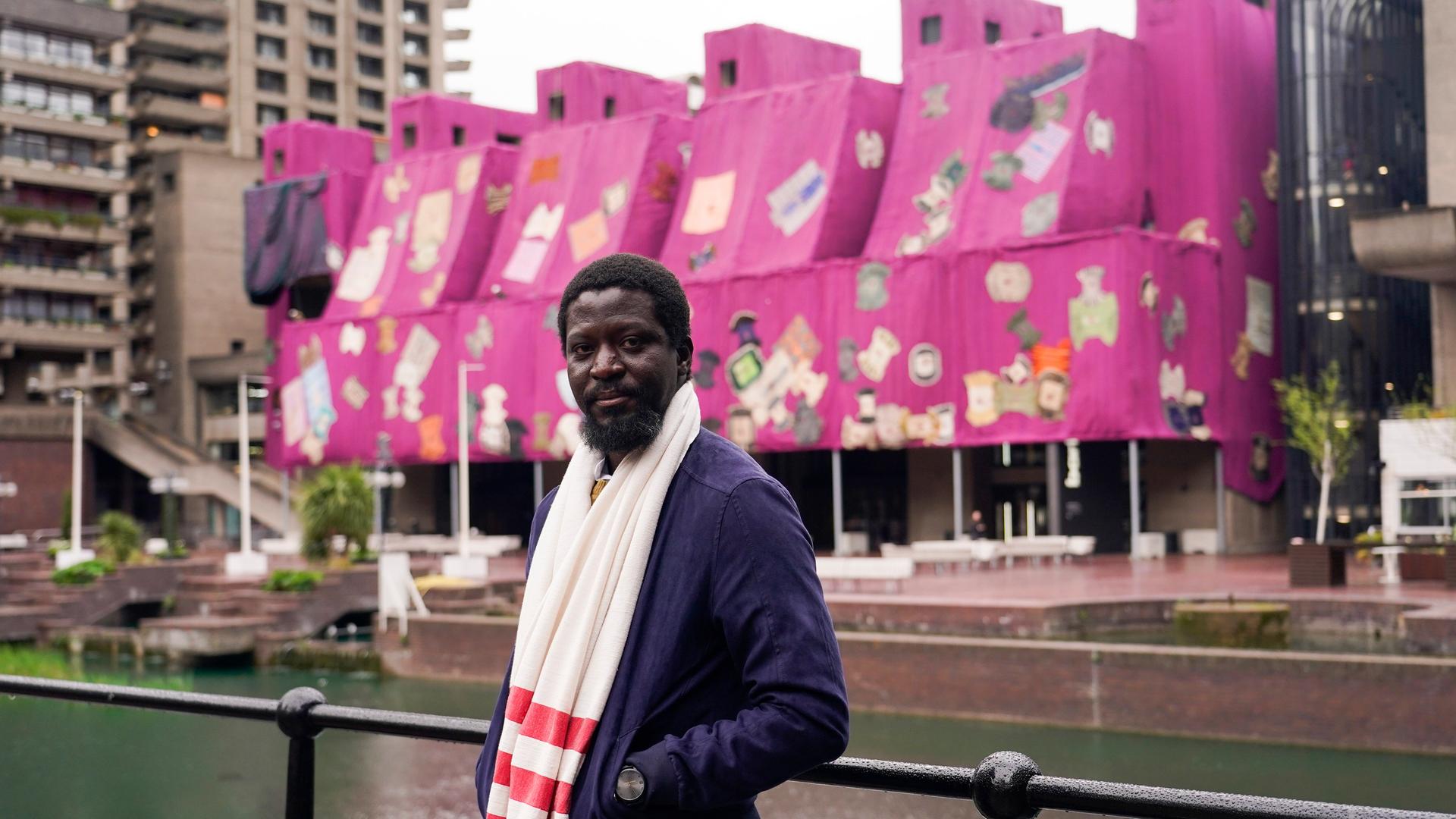 Der ghanaische Künstler Ibrahim Mahama posiert im Vordergrund seines Kunstwerks Purple Hibiscus vor dem Barbican Centre in London. Der ghanaische Künstler Ibrahim Mahama posiert im Vordergrund seines Kunstwerks Purple Hibiscus vor dem Barbican Centre in London.