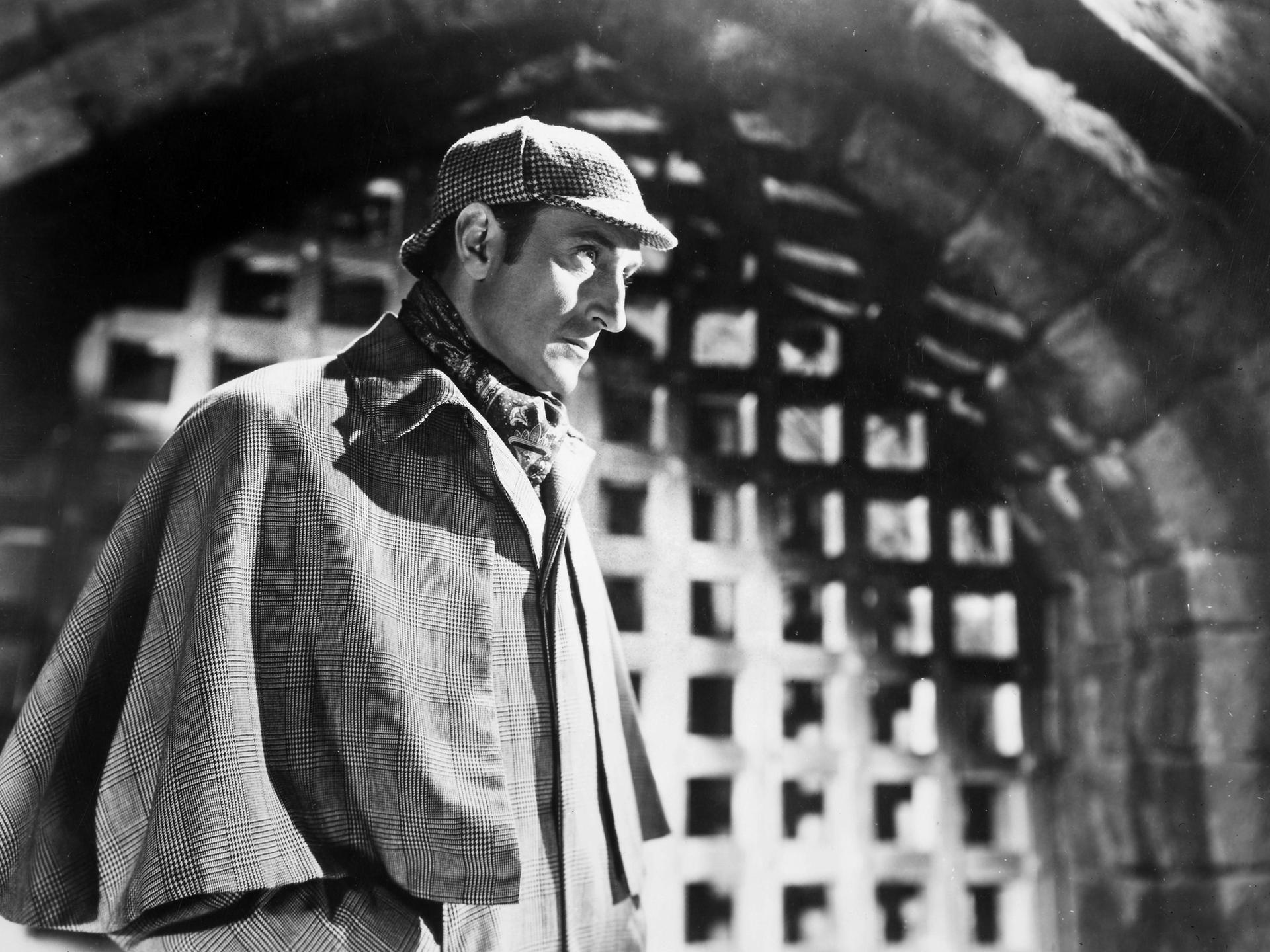 Schwarzweißfoto des Schauspielers Basil Rathbone in der typischen Montur von Sherlock Holmes