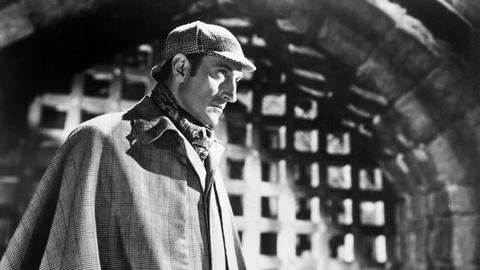 Schwarzweißfoto des Schauspielers Basil Rathbone in der typischen Montur von Sherlock Holmes