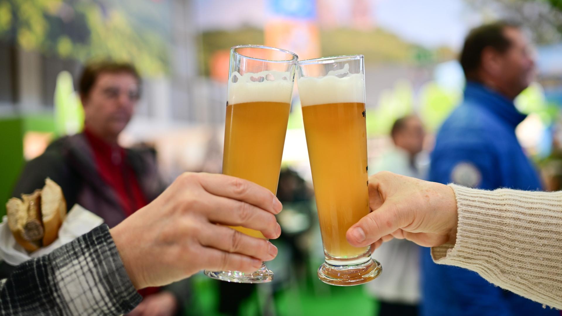 Zwei Hände stoßen mit Biergläsern an