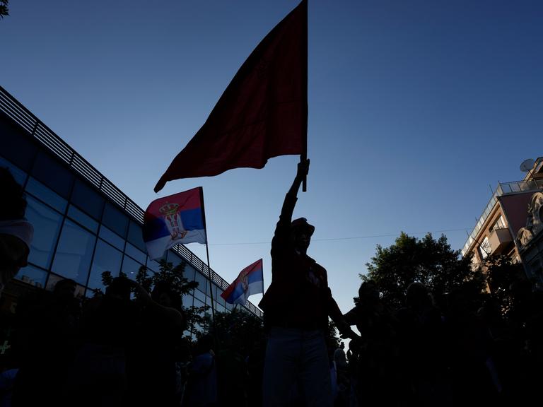 Ein Mann hält eine Flagge in den Himmel. 