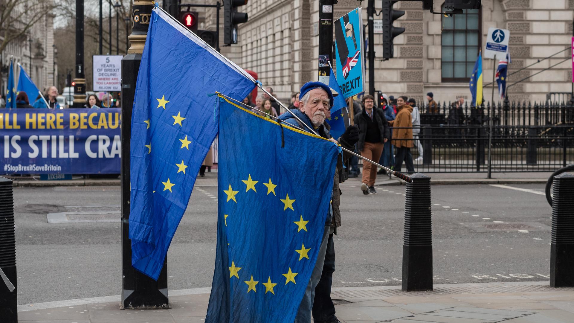 Ein alter Mann trägt in einer Londoner Straße zwei EU-Fahnen zum Protest gegen den Brexit. 