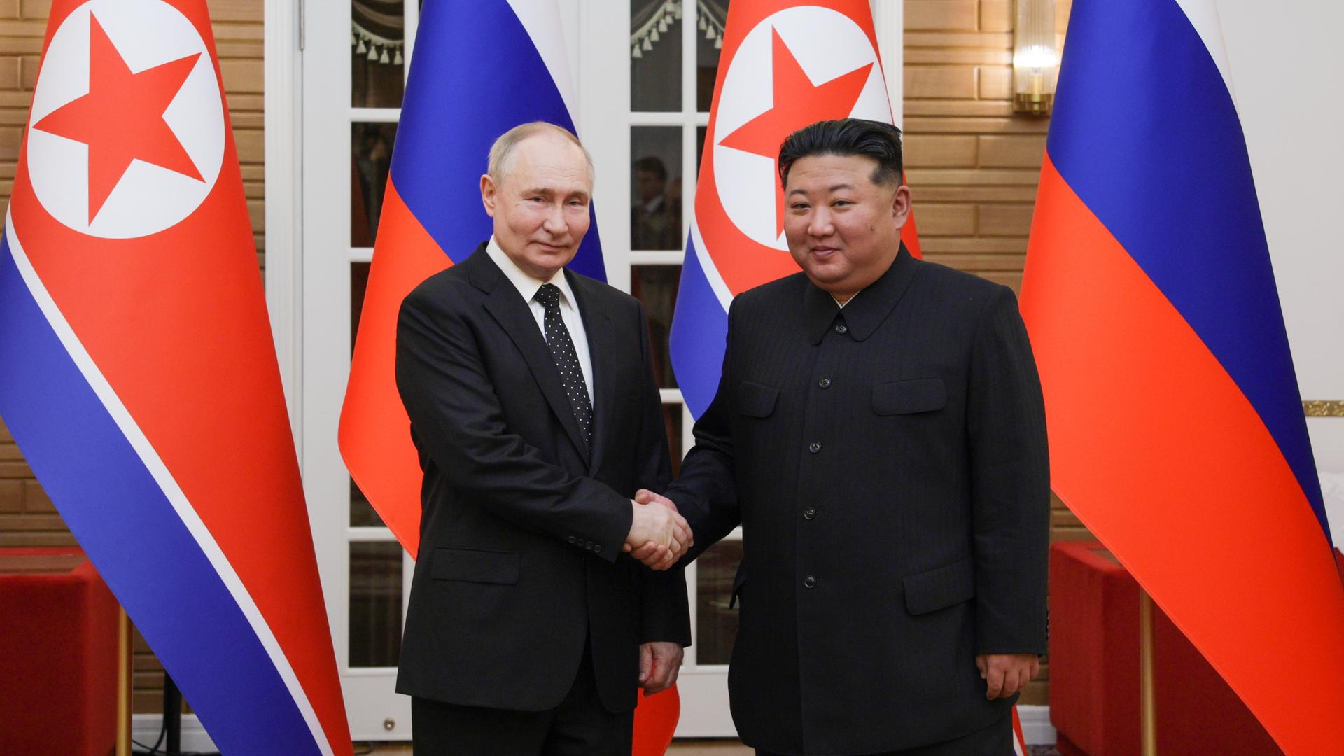 Der russische Präsident Wladimir Putin mit dem nordkoreanischen Staatschef Kim Jong-un vor Fahnen. 
