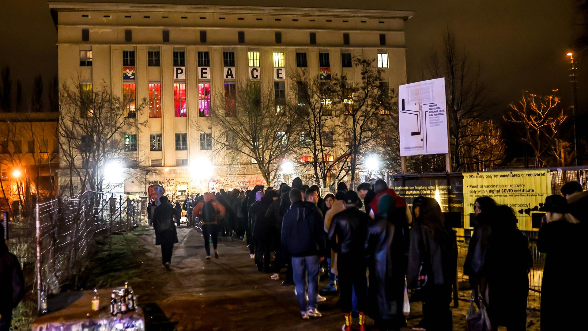 Menschenschlange wartender Clubbesucher vor dem Berliner Club Berghain mit PEACE-Schild an der Fassade