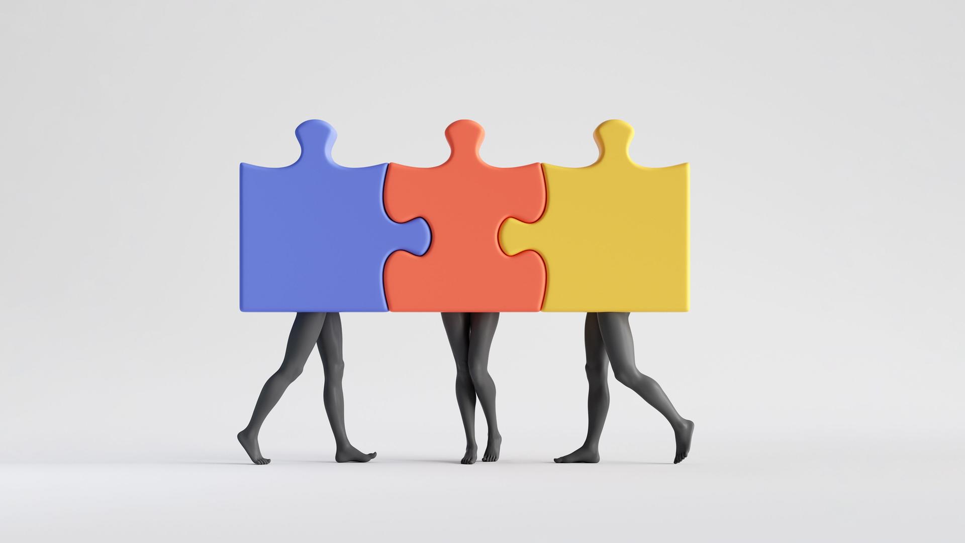Schwarz-Weiß-Aufnahme dreier Personen, deren Beine zu sehen sind und deren Oberkörper hinter farbigen, ineinandergesteckten Puzzleteilen verborgen sind.