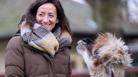 Das Bild zeigt die lächelnde Christina Geiger in einer Aussenaufnahme mit einem Zootier.