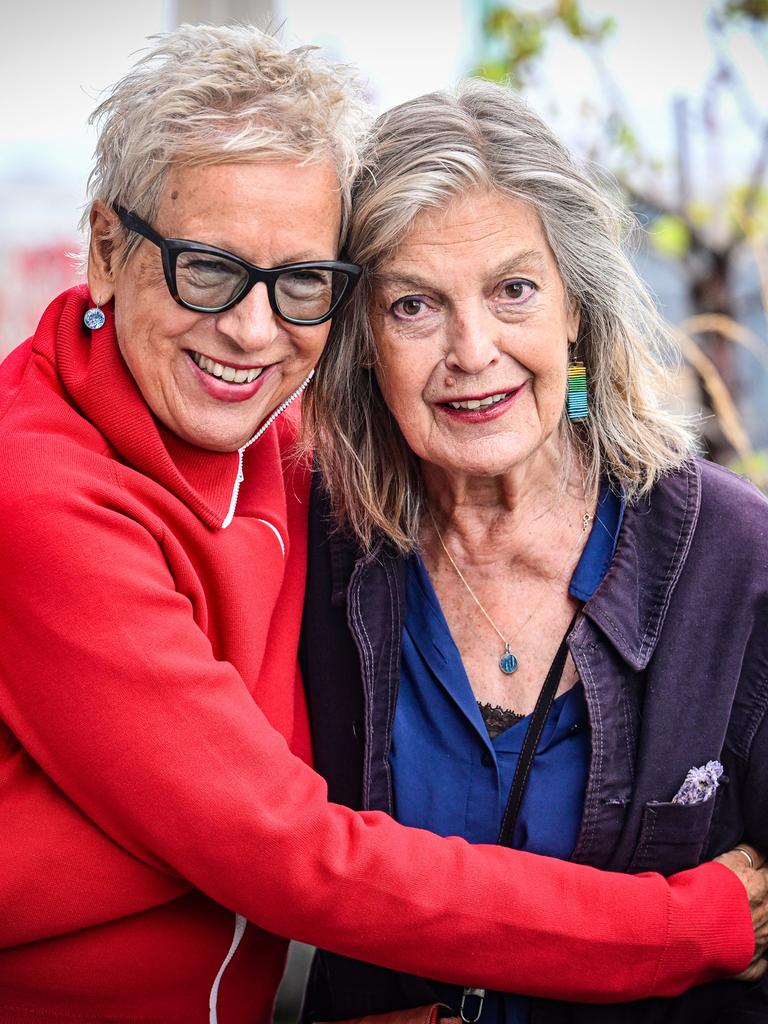 Doris Dörrie ist links im Bild auf einem Balkon, sie umarmt Angela Winkler. Die 71-jährige Dörrie trägt eine rote Jacke und hat eine Brille mit dunklen Gestell auf. Winkler hat lange Haare und trägt ein blaues Oberteil unter lilafarbener Jacke. Doris Dörrie ist links im Bild auf einem Balkon, sie umarmt Angela Winkler. Die 71-jährige Dörrie trägt eine rote Jacke und hat eine Brille mit dunklen Gestell auf. Winkler hat lange Haare und trägt ein blaues Oberteil unter lilafarbener Jacke.
