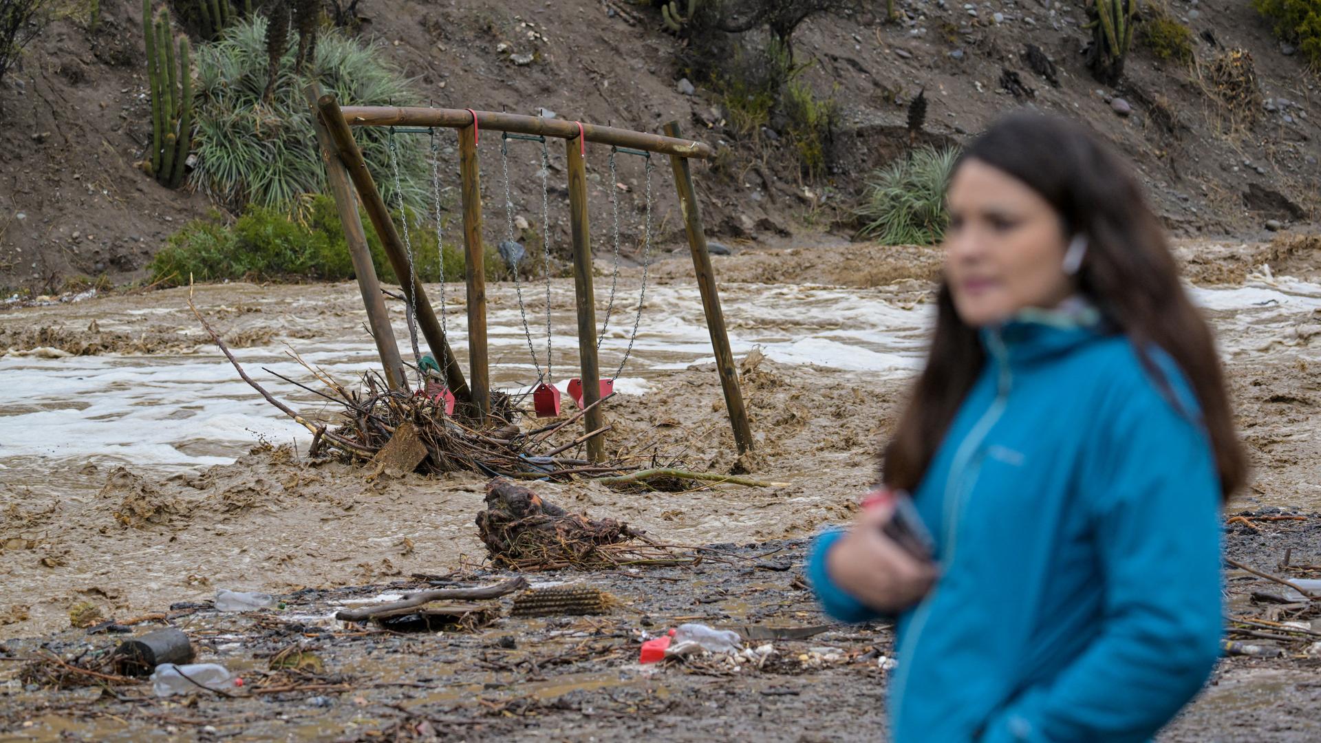 Das Bild zeigt eine verschwommen fotografierte Frau und einen von Fluten demolierten Spielplatz.